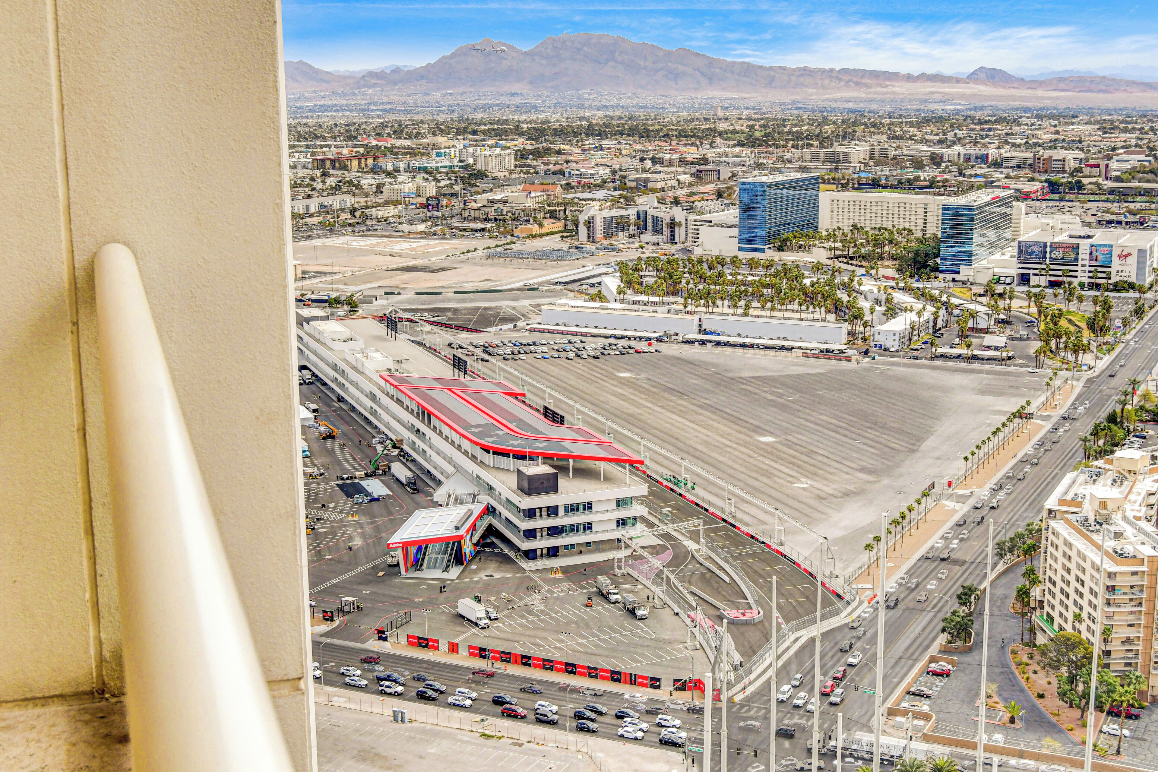Un hôtel moderne doté d’un toit plat, de plusieurs niveaux de stationnement et offrant une vue sur un paysage urbain avec des montagnes en arrière-plan.