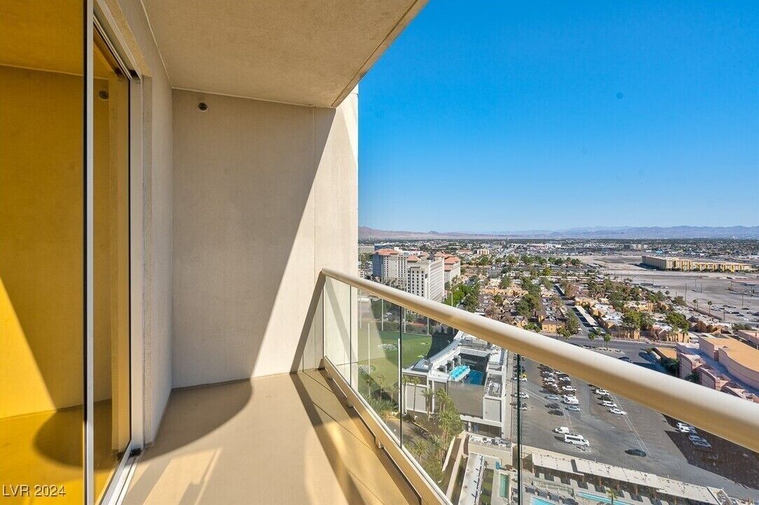 A balcony with a clear view of a cityscape, including buildings and a parking lot.