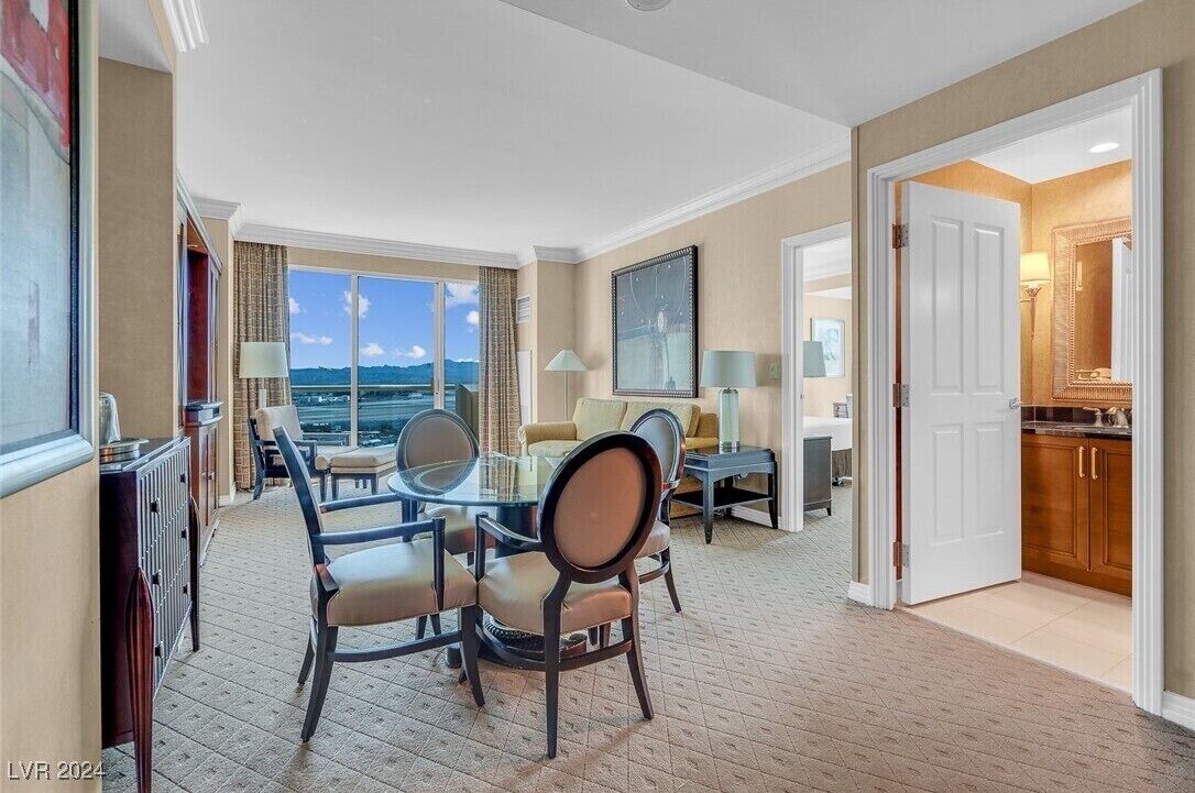 A hotel room with a dining area, a living room with a view, and a kitchen.