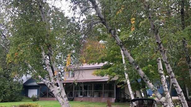 A lakeside property with a dock, a wooden deck, and a house with a porch. - Whitney Landing: A Lakeside Getaway on Upper Cold Stream Pond (Lincoln)