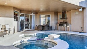 Un espace piscine comprenant un jacuzzi, du mobilier d’extérieur et un barbecue.