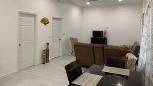 Un comedor con una mesa, sillas, ventilador de techo y televisor sobre un mueble.