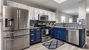 A modern kitchen with stainless steel appliances, blue cabinets, and a patterned backsplash. - Cozy Home in Downtown Fishers (Fishers)