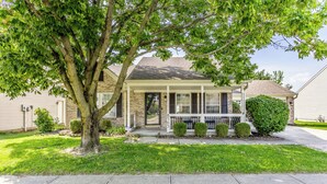 A two-story house with a covered porch, a brick facade, and a well-maintained lawn. - Cozy Home in Downtown Fishers (Fishers)