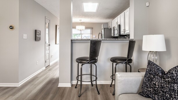 A modern kitchen with a central island, bar stools, and a dining area with a sofa and pillows. - Cozy Home in Downtown Fishers (Fishers)