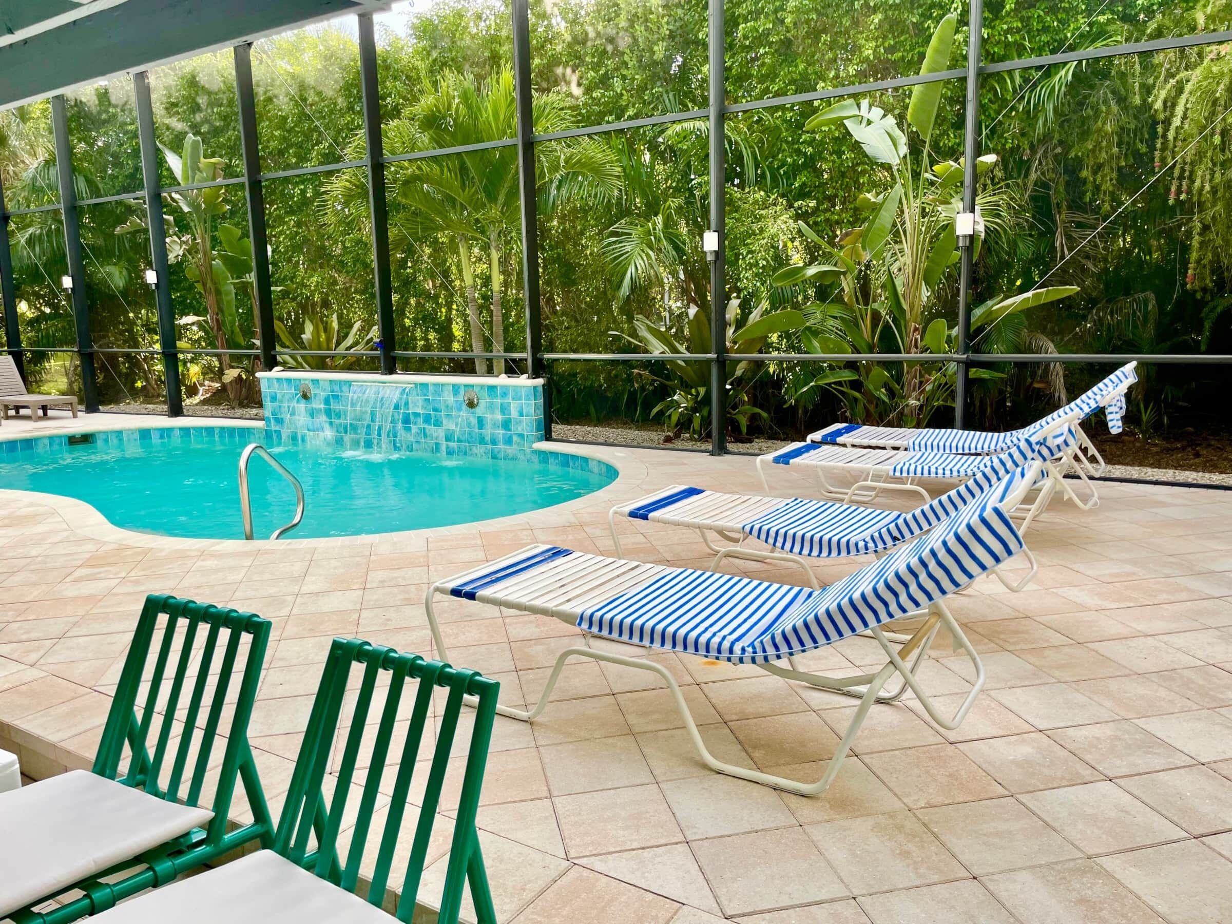 Un espace piscine doté de chaises longues et d’une petite cascade décorative.