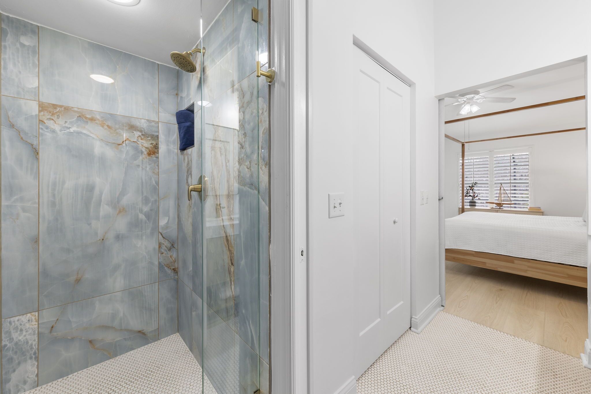 Une salle de bain moderne avec une douche à parois de verre, une porte blanche et une chambre à coucher avec un lit et une fenêtre.