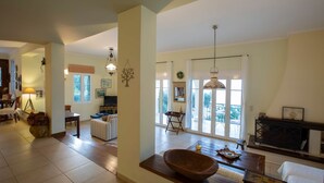 A spacious living area with a large window, a wooden bowl centerpiece, and a fireplace. - Boutique Villa Andronice with amazing view at the Ionian Sea (Tsoukalades)