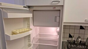 Frigorifero aperto con ripiani multipli e vano congelatore.