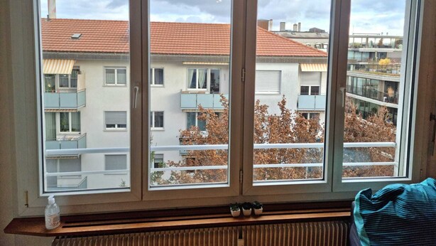 Una stanza con un'ampia finestra che si affaccia su una zona residenziale con numerosi edifici e balconi.