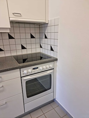 Uma cozinha compacta com forno embutido, fogão e micro-ondas.