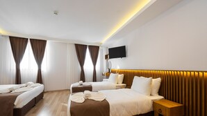 Habitació d'hotel amb dos llits, un televisor fixat a la paret i un panell de fusta al capçal.