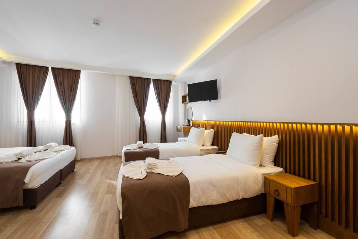 A hotel room with two beds, a TV mounted on the wall, and a wooden headboard.