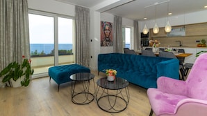 A modern living room with a blue sofa, a pink chair, and two round tables. - Villa Marko (Makarska)