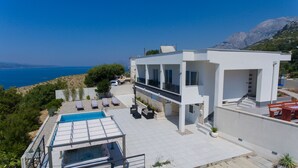 A modern villa with a swimming pool, outdoor seating, and a view of the sea. - Villa Marko (Makarska)