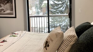 Ein Schlafzimmer mit Bett, einem Fenster mit Blick auf eine verschneite Landschaft und einem gerahmten Bild an der Wand.