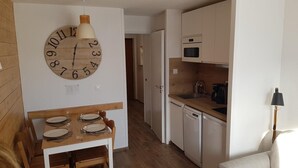 A compact kitchen with a wooden clock, a dining table with chairs, and a microwave. - Studio 4 P amazing vue (Avoriaz)