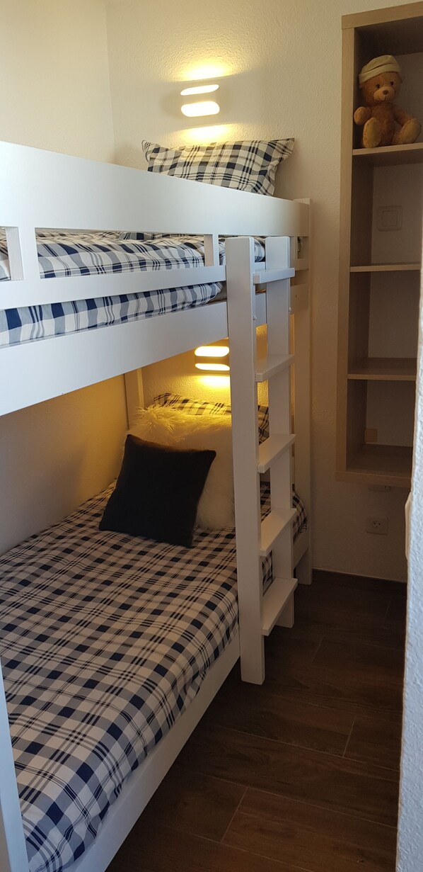 A bunk bed with a checkered bedspread, a black pillow, and a shelf with a teddy bear. - Studio 4 P amazing vue (Avoriaz)