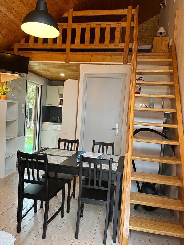 A dining area with a table and chairs, a staircase, and a kitchen in the background.