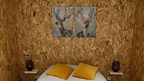 A bedroom with a wooden wall, a bed with white bedding, two yellow pillows, and two wall-mounted nightstands with lamps. - Chalet Capucine 1 in the heart of the Vosges mountains (Gérardmer)