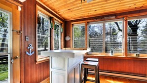 Un intérieur en bois avec un comptoir de cuisine, un évier et une fenêtre ornée d’une pancarte indiquant : « BIENVENUE au bord du lac ».