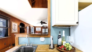 Une cuisine dotée d’un plan de travail en bois, d’un évier en acier inoxydable, d’un ventilateur de plafond et d’un saladier rempli de fruits.