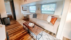 A cozy living area with a sofa, ottoman, and a small table with a tray. - RV There Yet? Lake view at PK.  (Graford)