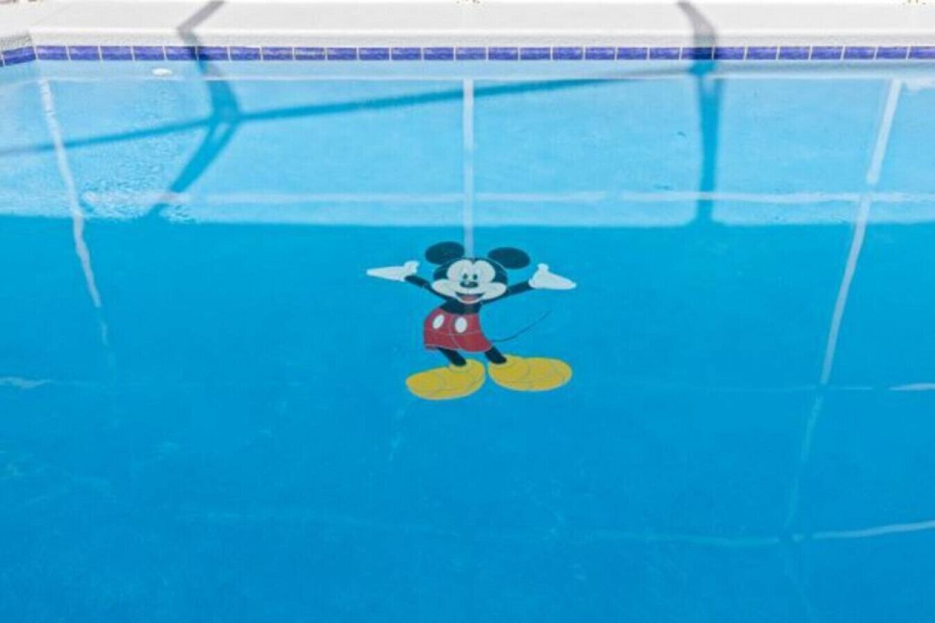 A swimming pool with a Mickey Mouse mural on the wall.