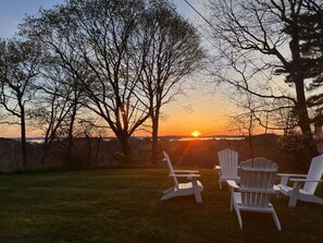 A sunset view with three Adirondack chairs in a grassy area. - Private - Ocean View, Walk to Acadia or Bar Harbor (Bar Harbor)