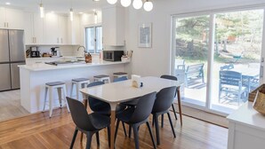 Une cuisine moderne avec des meubles blancs, un îlot central et des tabourets de bar.