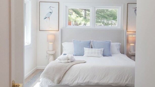 Une chambre à coucher avec un grand lit, une fenêtre et un tableau encadré accroché au mur.