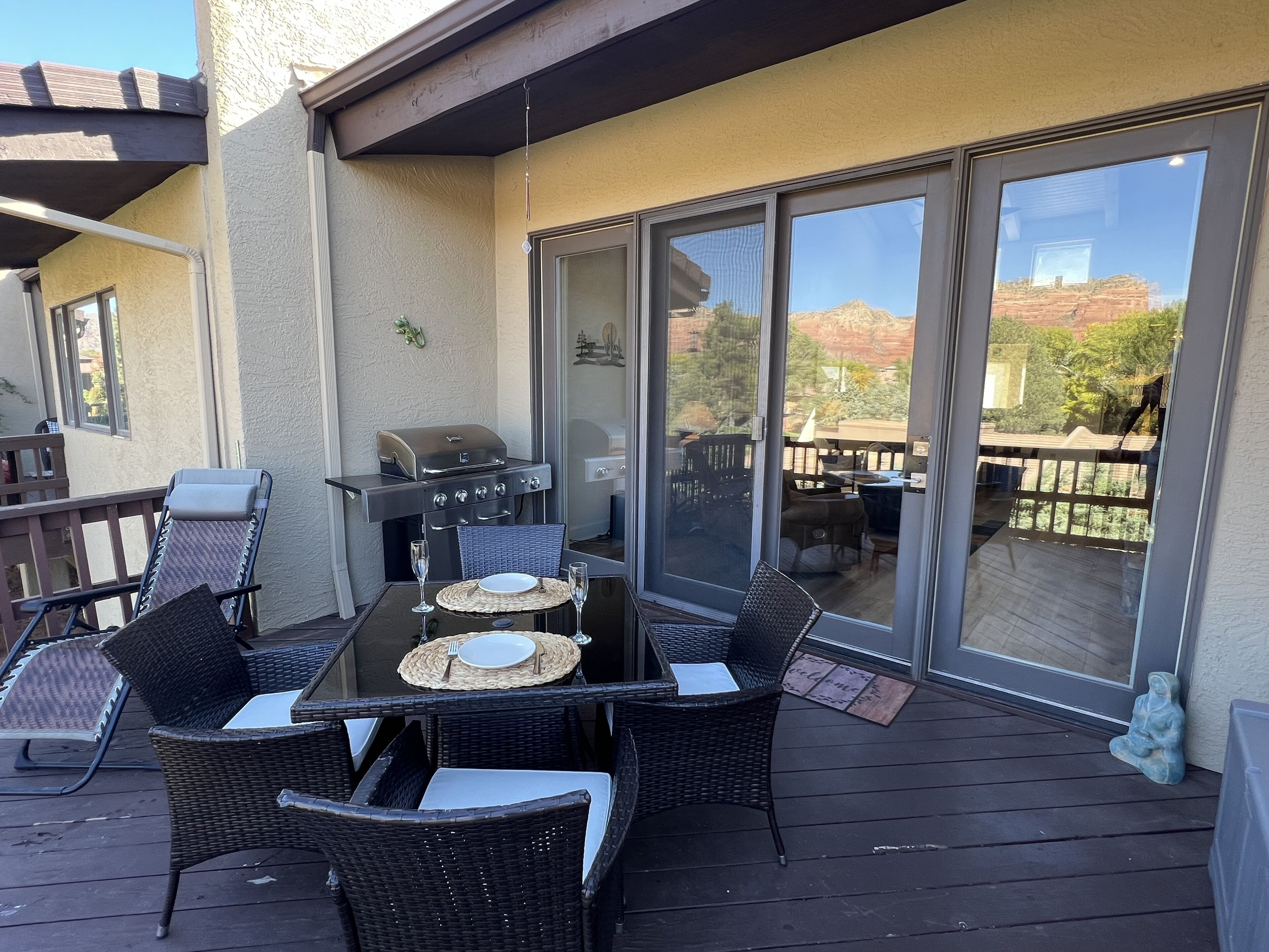 Eine Terrasse im Freien mit einem Tisch für zwei Personen, einem Grill und Korbstühlen.