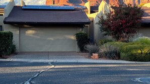 A residential house with a garage, solar panels, and a mountain backdrop. - Remodeled Sedona Townhome on Golf Course – Stunning Red Rock Views !!! (Sedona)