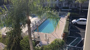 A swimming pool with a view of a parking area and a building in the background. - Vanderbilt Beach less than a mile! Dog friendly, Tropical Paradise! 3br & WiFi! (Naples)