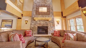 A cozy living room with a stone fireplace, wooden beams, and a high ceiling. - Perfect Ski Condo with hot tub Steps from the Super Bee & Golf Course CS325 (Copper Mountain)