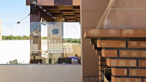 A view of a building's exterior with a glass window reflecting another building and a brick wall. - Cabanas Gardens,  6px, terrace and barbecue (Cabanas de tavira)