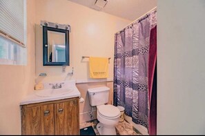 Een bad/douchecombinatie, een haardroger, handdoeken, toiletpapier