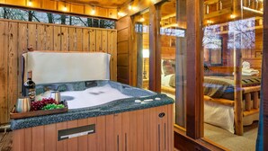 A wooden cabin interior with a hot tub, wooden walls, and a cozy bedroom visible through a glass door. - Spacious Cozy Cabin - Best of Both Worlds (Gatlinburg)