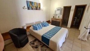 A hotel room with a bed, a chair, a nightstand, and a painting on the wall. - Self-contained 75 m2 apartment on the ground floor of a villa, air-conditioned, seafront (L'Île-Rousse)