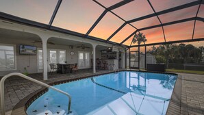 Une piscine intérieure dotée d’un toit en verre, un bar et une terrasse avec des sièges extérieurs.