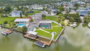 Une propriété située au bord de l’eau, dotée d’un quai, d’une piscine et d’une grande maison avec un patio couvert.