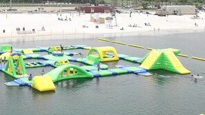 An outdoor water play area with inflatable structures and a sandy beach in the background. - Pool-Dock-Kayaks-Ping Pong!! Waterfront paradise <3 (Hernando Beach)