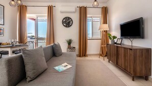 Ett modernt vardagsrum med en soffa, en tv och en matplats med ett bord och stolar.