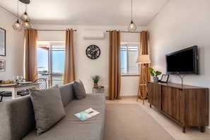 Un soggiorno moderno con divano, TV e zona pranzo con tavolo e sedie.