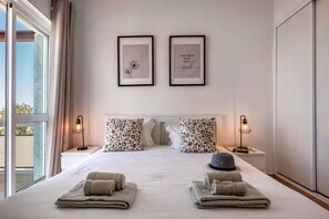 A hotel room with a large bed, two framed pictures on the wall, a window with curtains, and a nightstand with a lamp. - Apartment in the city center! (Faro)