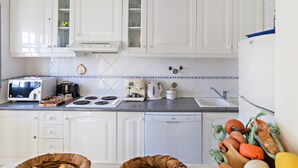 A kitchen with white cabinets, a microwave, a toaster, a coffee maker, and a dishwasher.