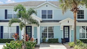 A two-story building with a light blue exterior, dark blue shutters, and a central entrance with a door. - Windsor Hills Home w/ Pool 2 miles from Disney! (Kissimmee)
