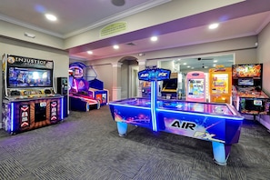 Un área de juegos con máquinas recreativas, incluyendo 'Injustice', 'Air FX' y 'The Zone'.