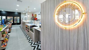 A modern hotel lobby with a central reception desk, a large illuminated sign, and a patterned floor. - Windsor Hills Home w/ Pool 2 miles from Disney! (Kissimmee)
