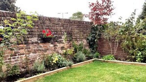A brick wall with a garden bed and a grassy area in front. - Entire House in Canterbury Centre - Free Parking - WiFi (Canterbury)